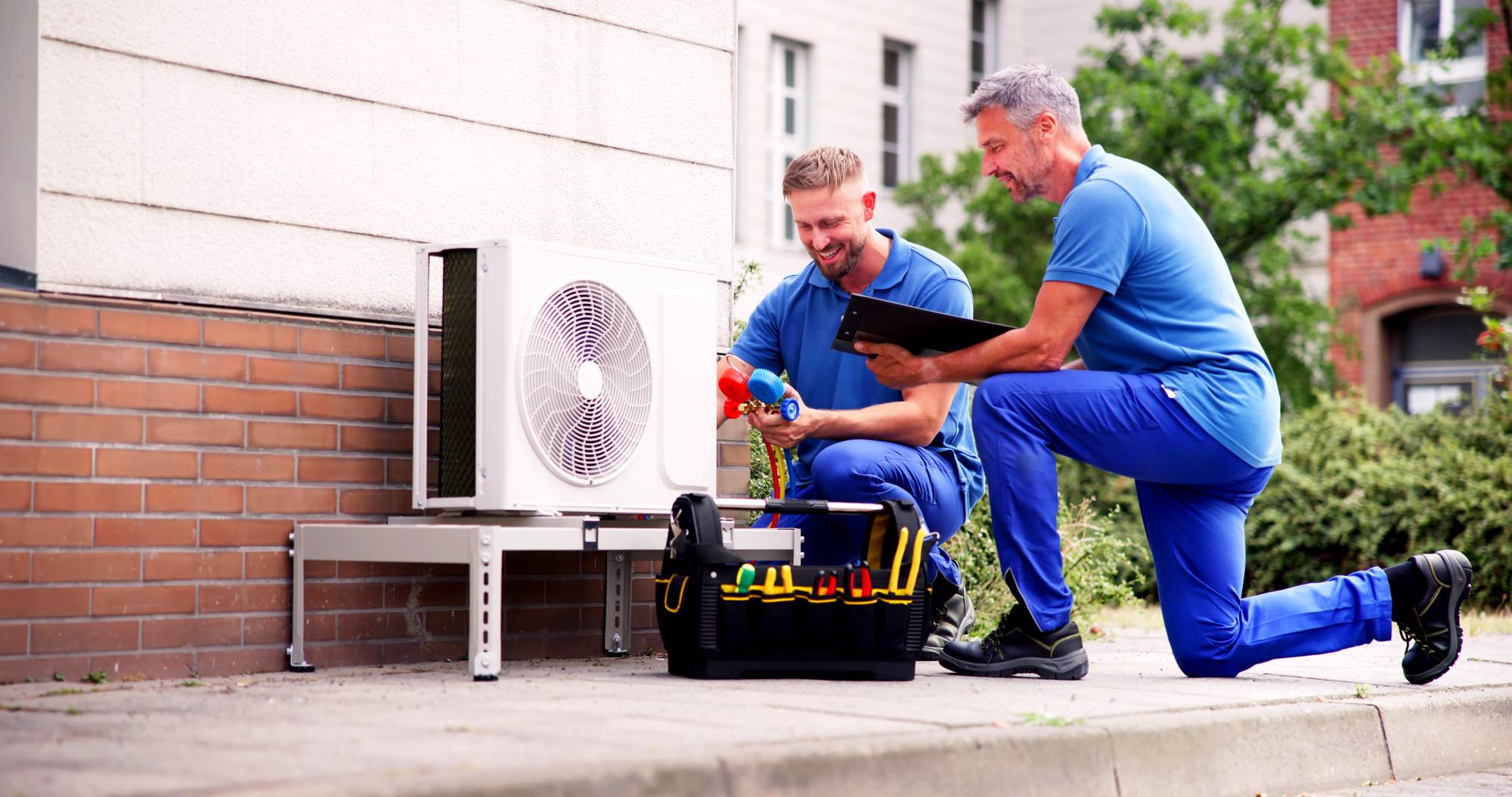 HVAC technicians in Oregon reviewing an installation checklist beside a condenser unit